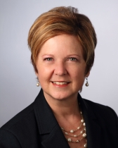 Head shot of Gloria Larkin with short blonde hair and a black blazer