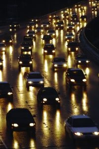 Freeway traffic in the evening, dozens of cars driving in the dark with headlights on