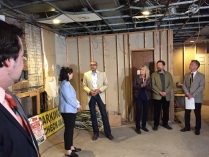 A group of individuals stand around a partial complete building under renovation having conversations