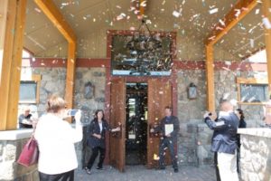 Photo of confetti falling while people watch, taking photos of the doors open to a new business and event center