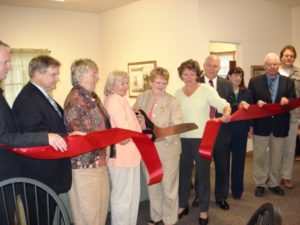 Cutting a large red ribbon are a group of representatives of Grimm Construction