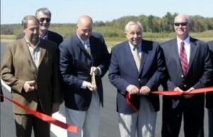 George Strunk, PM Airport Authority Chairman, cuts a large red ribbon on the newly completed runway extension surrounded by fellow board members Dave Moyer, Karl Weiler, Joe Miller and John Lamberton